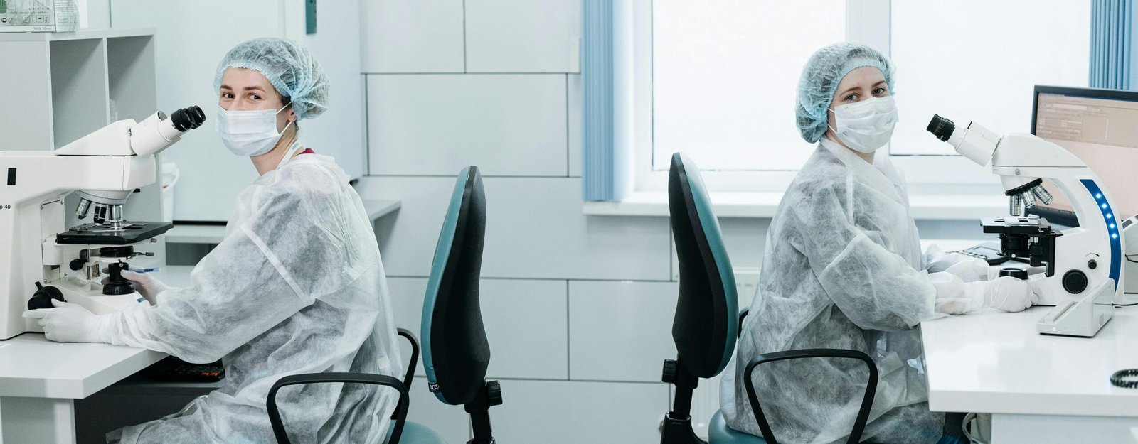 Two female scientists working with microscopes in a laboratory setting.